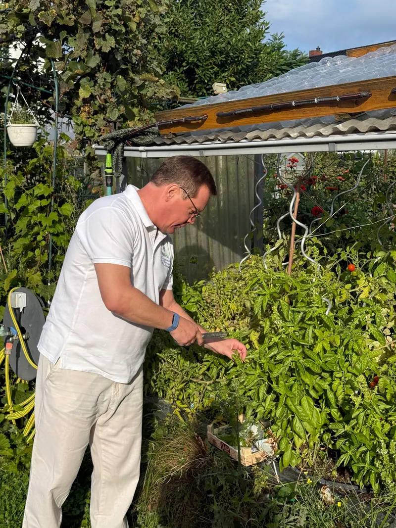 Maik Roemer schneidet frische Kräuter im Garten
