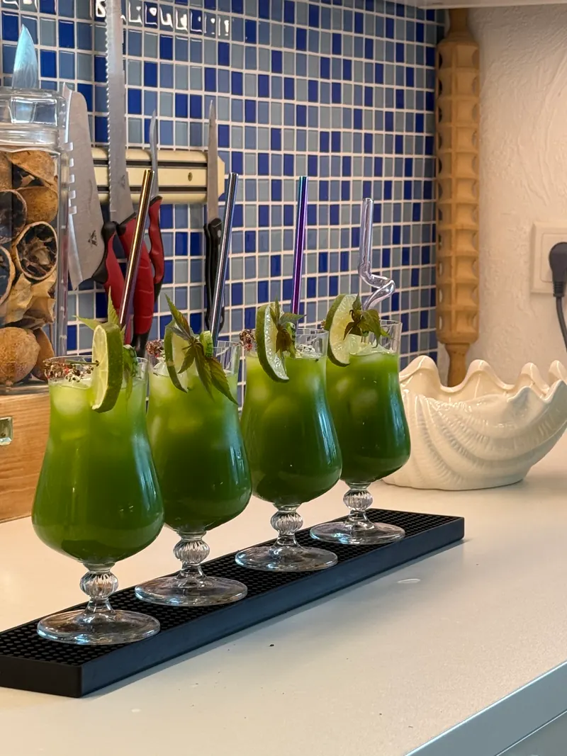 Vier grüne Low-Carb-Cocktails mit Limette vor blauem Fliesenmosaik